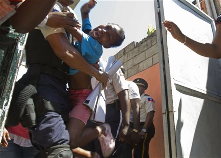 An orphan reacts as she is carried away by a police officer during the closure of the Son of God orphanage in Port-au-Prince, Haiti, on Friday. View PhotoBlog for more coverage. 